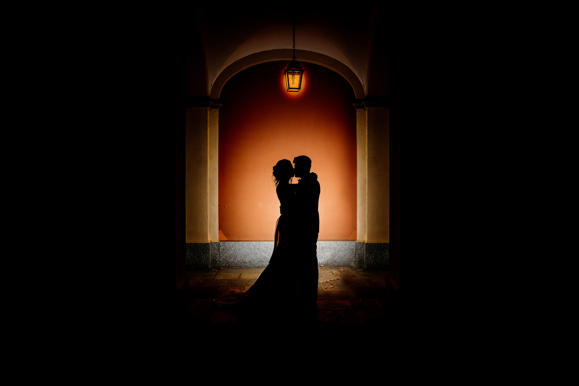 Matrimonio a Villa Fiorita (Asti). Foto finale, silhouette degli sposi che si baciano. Flash esterno puntato contro il muro